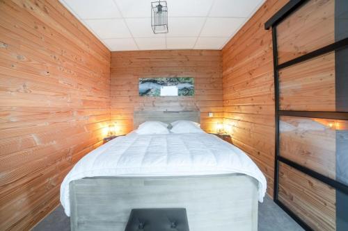 a bedroom with a bed in a wooden wall at Chalet charmant à Saint-Sylvestre avec jardin 32 m² in Saint-Sylvestre