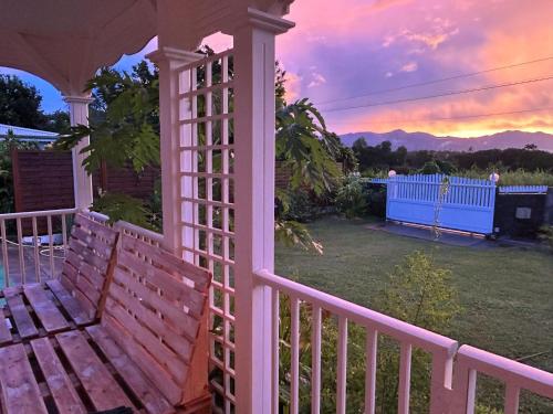 a pink gazebo with a bench and a sunset at Maison confortable avec jardin à Lamentin in Lamentin