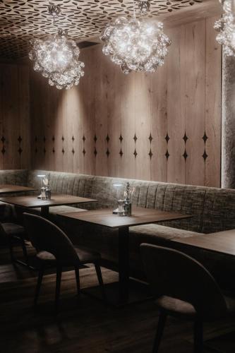a dining room with tables and chairs and chandeliers at Hotel Berghof - St Johann in Salzburg in Sankt Johann im Pongau