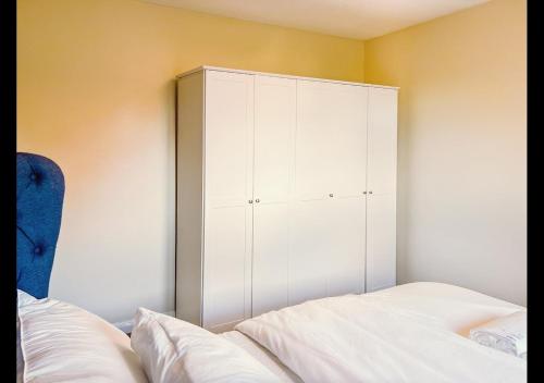 a bedroom with a white cabinet next to a bed at Cambridge Apartment at St Neot in Eaton Socon