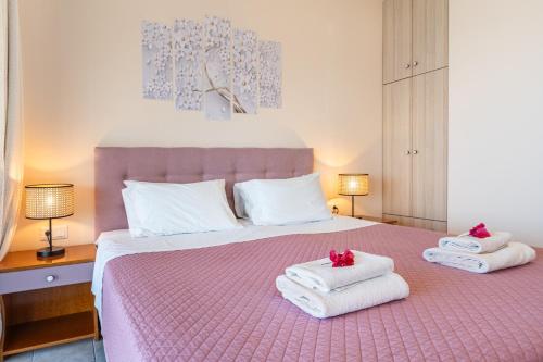 a bedroom with a pink bed with towels on it at Lido Sofia Apartments in Agios Gordios