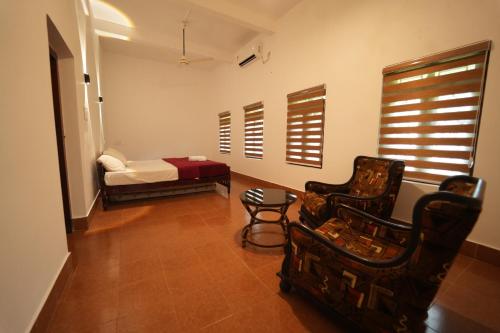a bedroom with a bed and two chairs and a table at Chandralayam Heritage Homestay in Bekal