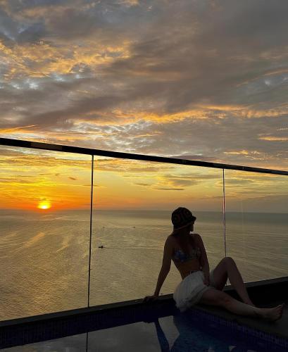 a woman sitting in a pool watching the sunset at Mandala Pearl Azure Retreat in Ấp Nhơn Long