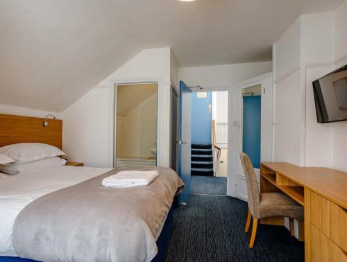 a hotel room with a bed and a desk and a desk at Tommy Jacks Beach Apartments in Bude