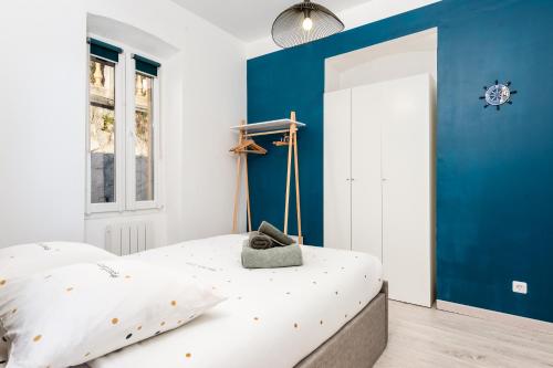 - une chambre avec un mur bleu et un lit dans l'établissement CONCORDIA - Agréable deux pièces - Menton Garavan - Vue Mer, à Menton