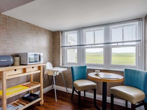 a room with a table and chairs and a microwave at Tommy Jacks Beach Apartments in Bude