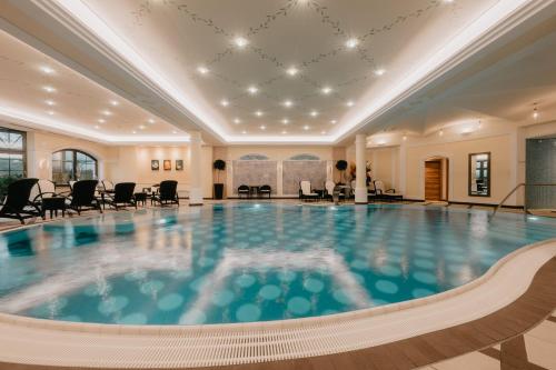 a swimming pool in a hotel with chairs and tables at Hotel Berghof - St Johann in Salzburg in Sankt Johann im Pongau