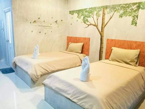 two beds in a room with a tree on the wall at Phurang Hill Resort in Kanchanaburi