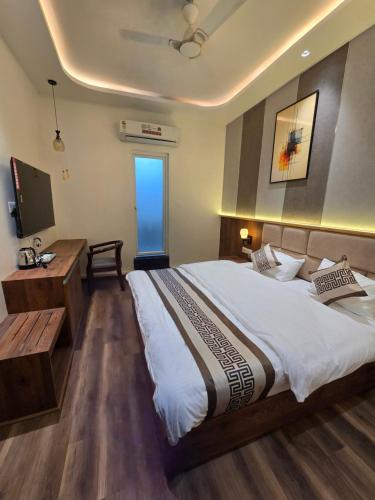a bedroom with a bed and a desk and a television at Hotel Fortune in Ayodhya