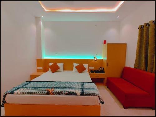 a bedroom with a bed and a red couch at Hotel Ramay Palace in Ayodhya