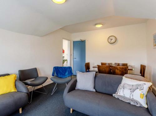 a living room with two couches and chairs and a clock at Tommy Jacks Beach Apartments in Bude