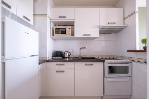 une cuisine blanche avec des armoires blanches et un micro-ondes dans l'établissement Appartement Exquis à La Défense, à Courbevoie