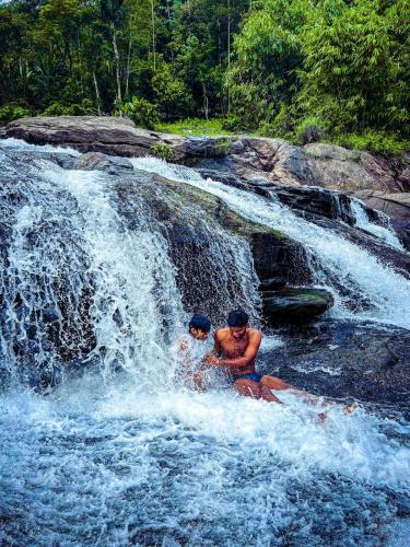 two men riding a raft in a waterfall at Tent stay mankulam in Viripara