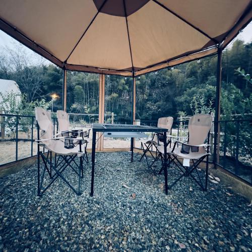 a glass table with chairs and an umbrella at NTV Smoky Garden in Owariasahi