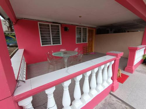 a pink house with a table and chairs on a balcony at Homestay Hajah Jamilah Sungai Tiram in Ulu Tiram
