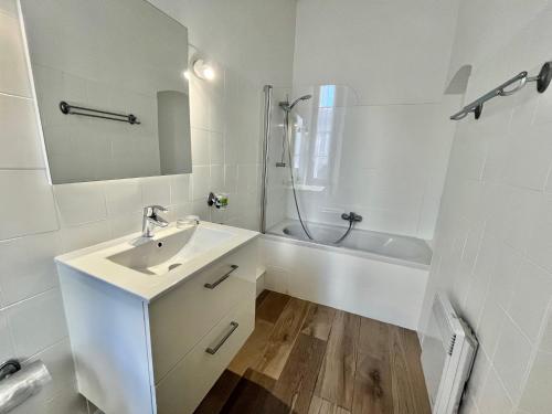 une salle de bain blanche avec un lavabo et une baignoire dans l'établissement Honore apartment 3 min from Palais des Festivals by Welcome to Cannes, à Cannes