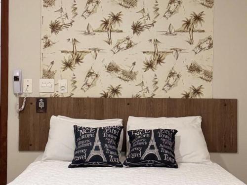 a bed with two pillows and a wallpaper with palm trees at KANKUN MOTEL E POUSADA -Adult only in Sorocaba
