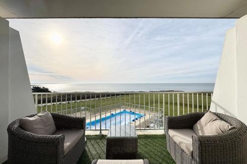 a balcony with two chairs and a swimming pool at Somptueux appartement - vue imprenable sur l'océan in Guidel