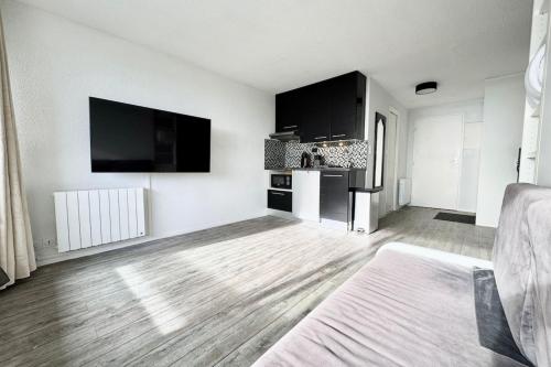 Il comprend un salon blanc doté d'une télévision à écran plat. dans l'établissement Studio Confort - Vue sur Mer - Balcon, à Guidel