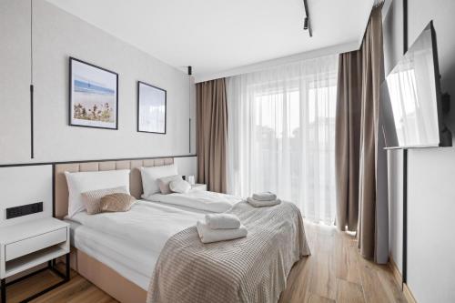 a bedroom with a white bed and a window at Rezydencja Merwede Aparthotel - My Rest in Gdańsk