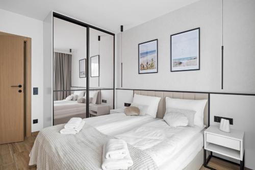 a bedroom with a large bed with white sheets at Rezydencja Merwede Aparthotel - My Rest in Gdańsk
