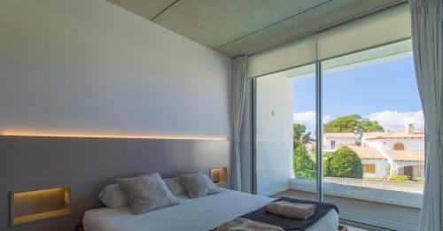 Un dormitorio con una cama y una ventana grande. en Villa Pau, en Playa de Muro