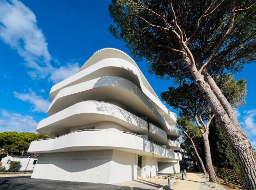 un bâtiment blanc avec un arbre devant lui dans l'établissement Grande Motte Coba - résidence standing, proximité plage, à La Grande Motte