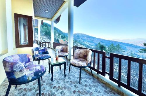 a balcony with chairs and a table and a view at The Mesmerizing Villa I Kufri I Nature Walk I Family Events & Bonfire I Memories & Enjoyment Villa I Operated by Exotic Stays in Kūfrī