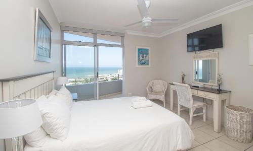 Un dormitorio con una cama y un escritorio y una ventana. en 53 Sea Lodge Umhlanga Rocks, en Durban