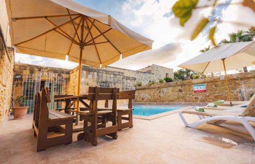 a patio with chairs and umbrellas next to a pool at Strawberry Hills in Żejtun