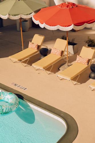 a group of chairs and umbrellas next to a swimming pool at Royal Sun Palm Springs in Palm Springs