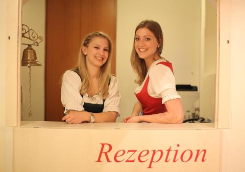 
two women standing next to each other in front of a sign at Hotel Rosenvilla in Salzburg
