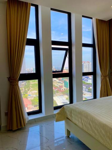 a bedroom with four windows and a bed with a view at The Vincent Apartment in Phnom Penh