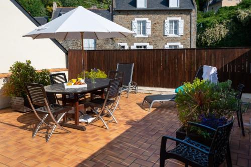 un patio avec une table, des chaises et un parasol dans l'établissement Les Reflets de la Houle, à Cancale