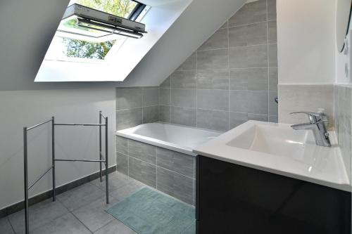 La salle de bains est pourvue d'un lavabo, d'une baignoire et d'une lucarne. dans l'établissement Lescale des douets fleuris, à Cancale