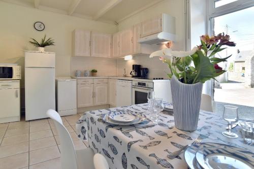 une cuisine avec une table avec un vase de fleurs dessus dans l'établissement Larmoricaine, à Cancale