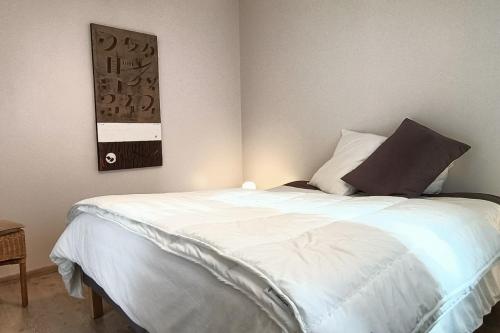 a bedroom with a white bed with a black pillow at Le petit chalet bleu in Cancale