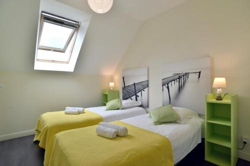 Cette chambre dispose de 2 lits avec des draps jaunes et d'une fenêtre. dans l'établissement Breizh emeraude, à Saint-Malo