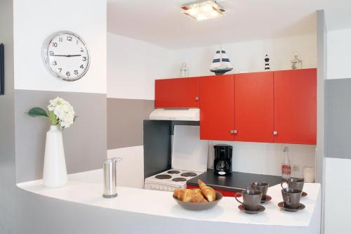 - une cuisine avec des placards rouges et un bol de pain dans l'établissement Comme à la maison, à Cancale