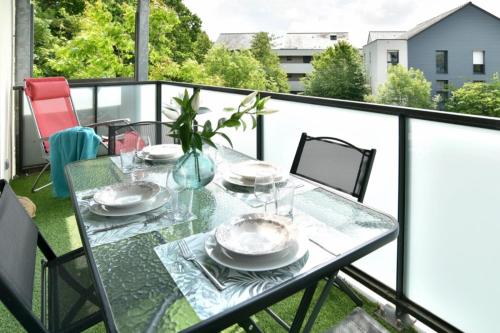 une table en verre avec des assiettes et des verres sur un balcon dans l'établissement Breizh emeraude, à Saint-Malo