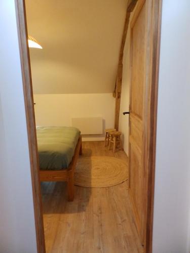 a small room with a bed and a wooden door at Gîte avec jacuzzi privatif - Haras Le Val Du Conte in Le Bouillon