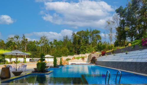a large swimming pool with blue water at The Grand Retreat - Chikmagalur in Chikmagalūr