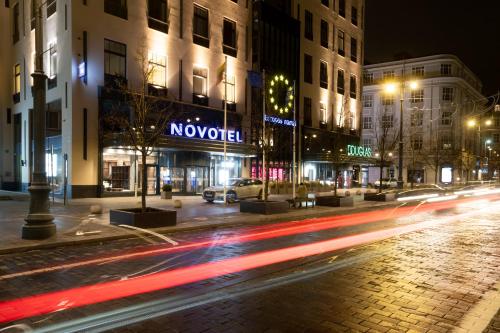 a city street at night with buildings and cars at Novotel Vilnius Centre in Vilnius