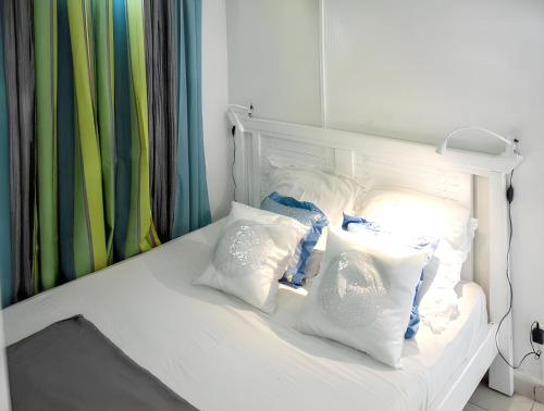 a white bed with white pillows on it at Bungalow charmant à Sainte-Rose avec terrasse et piscine in Sainte-Rose