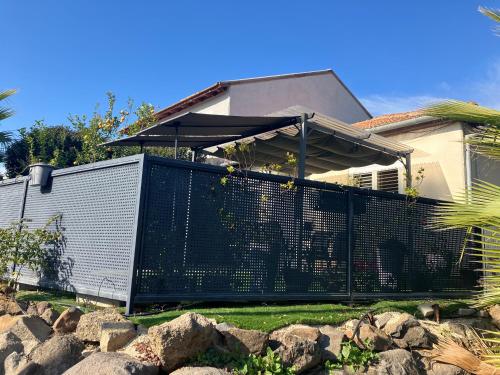 a fence with an umbrella in front of a house at Limor-resident in Qasrîne