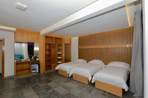 two beds in a bedroom with wooden walls at Sahara Beach in Tan-Tan Plage