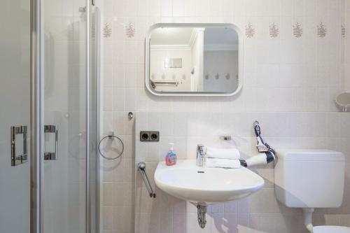 a white bathroom with a sink and a shower at Lütte Stuuv im Schlossgang in Husum