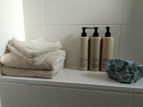 a shelf with three towels and a group of bottles at Cottage at Sea in Noordwijk aan Zee