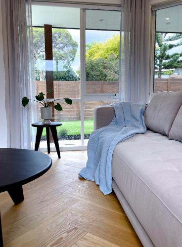 a living room with a couch and a large window at Bayside Retreat near beach and Frankston centre in Frankston