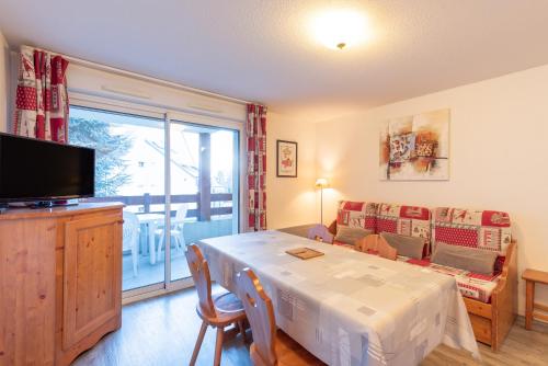 a living room with a dining room table and a television at T2 avec piscine couverte et parking in Saint-Lary-Soulan